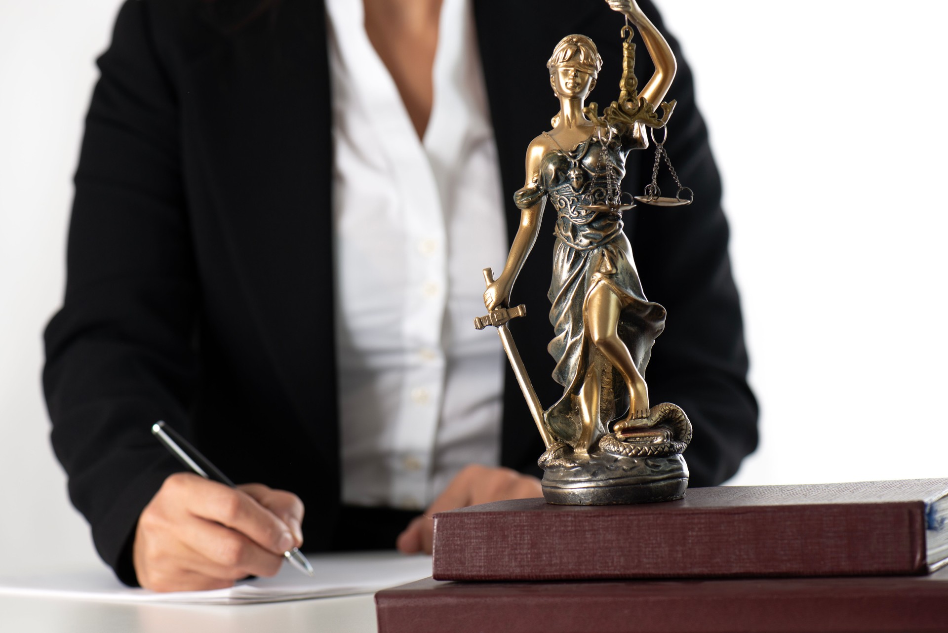 Lawyer Writing with Lady Justice Statue in Foreground